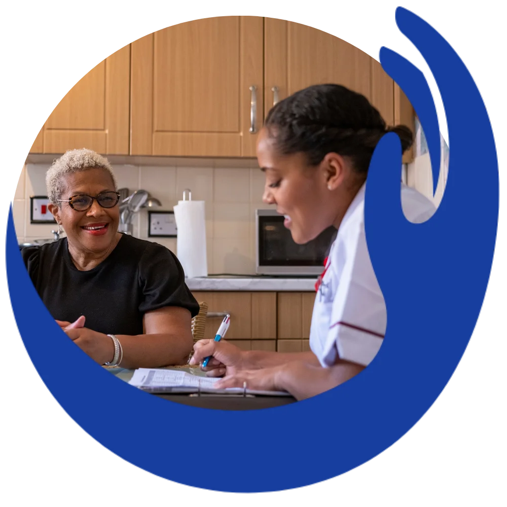 Nurse taking notes with woman in kitchen at home